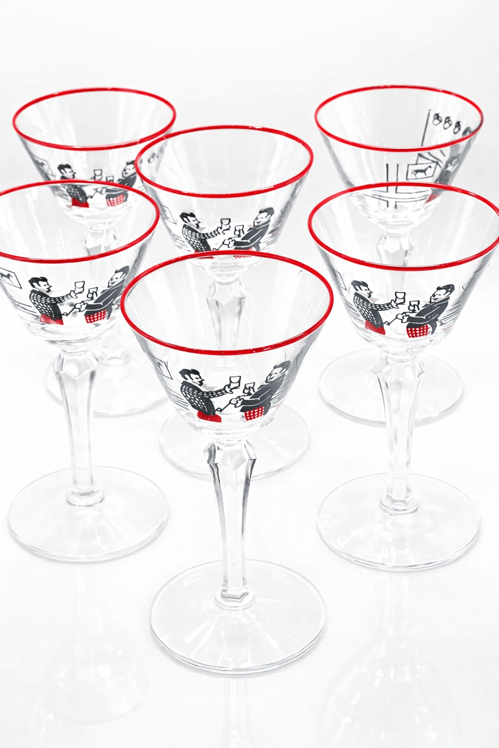 Set of six clear cocktail glasses with red rims and black and white illustrations on a white background