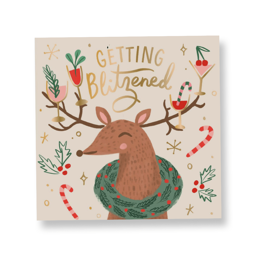 christmas cocktail napkin with a white background with scattered holly berries and candy canes, in the center is a reindeer with different cocktail glasses hanging from the antlers and the words "getting blitzened" in gold at the top