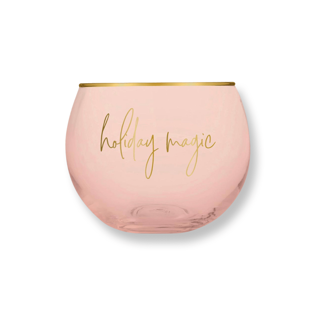 petite round cocktail glass in a blush color with a gold rim and gold script that reads "holiday magic"