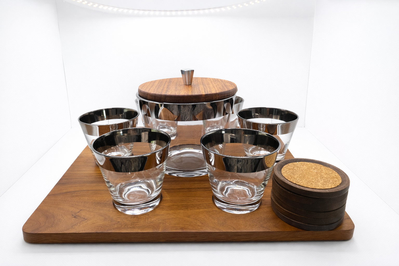 Set of glass tumblers with wooden and cork coasters on a white background