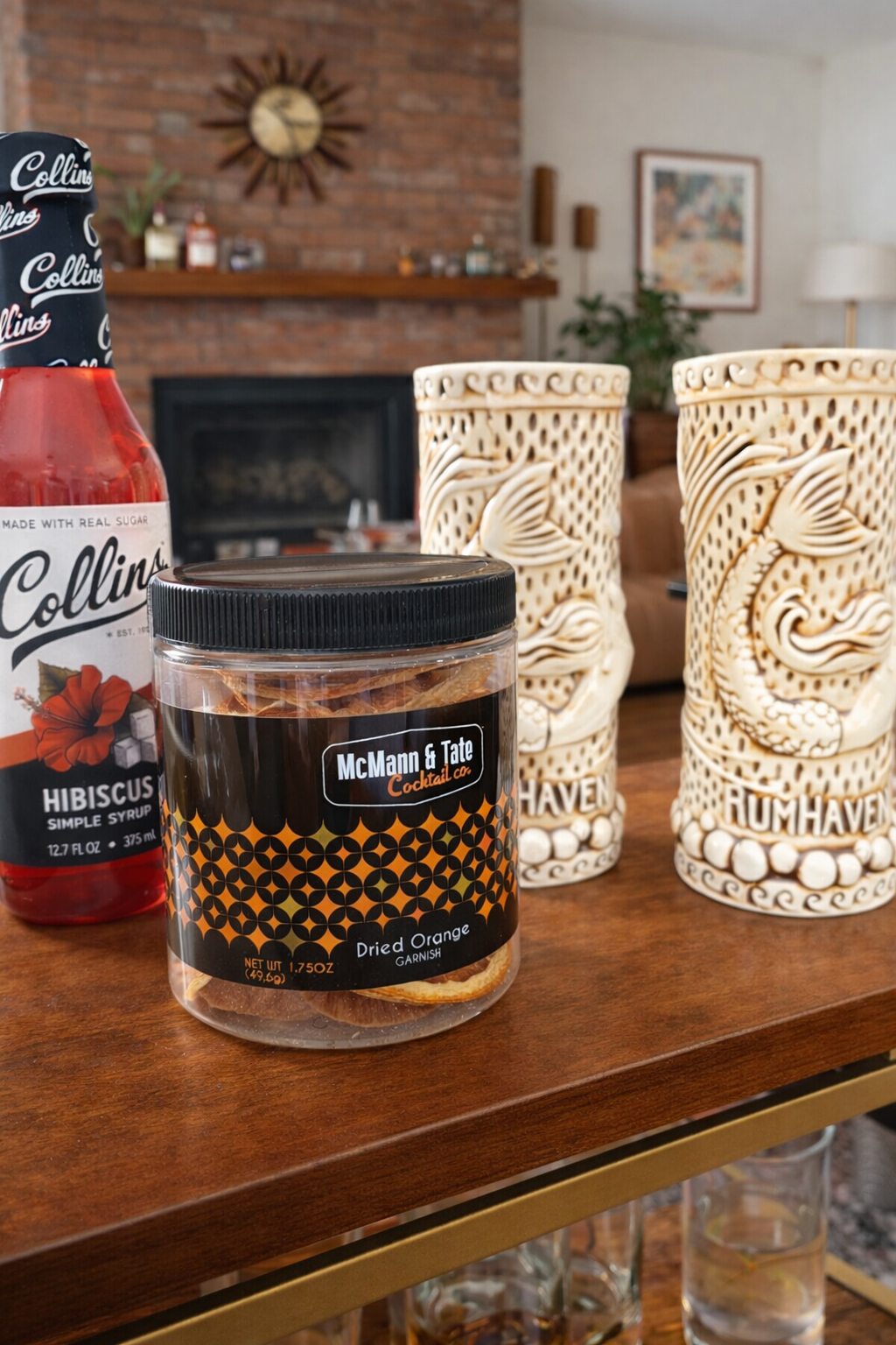 Collins hibiscus simple syrup and dried orange cocktail garnish styled with tiki mugs on a midcentury modern home bar setting.