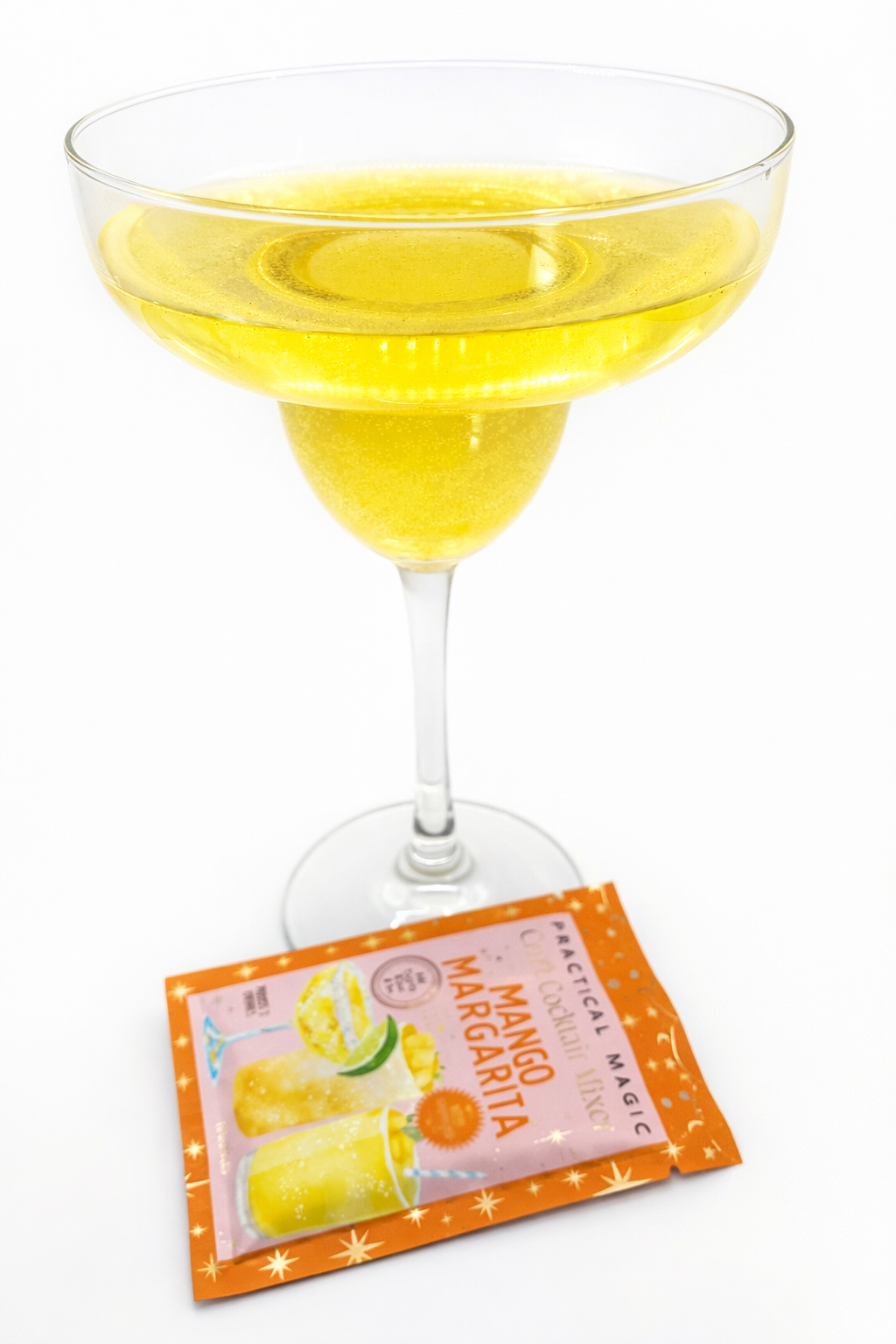 Prepared mango margarita cocktail in a coupe glass with Practical Magic mango margarita mixer packet