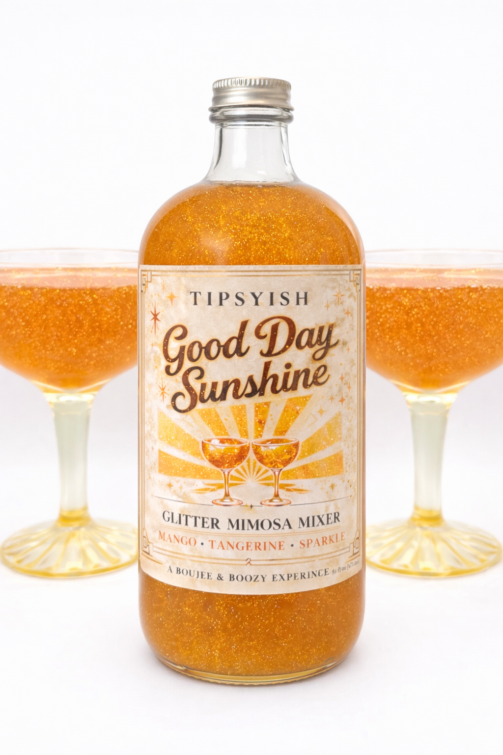 Tipsyish Good Day Sunshine glitter mimosa mixer with mango and tangerine in glass bottle, shown with sparkling mimosa coupe glasses on white background