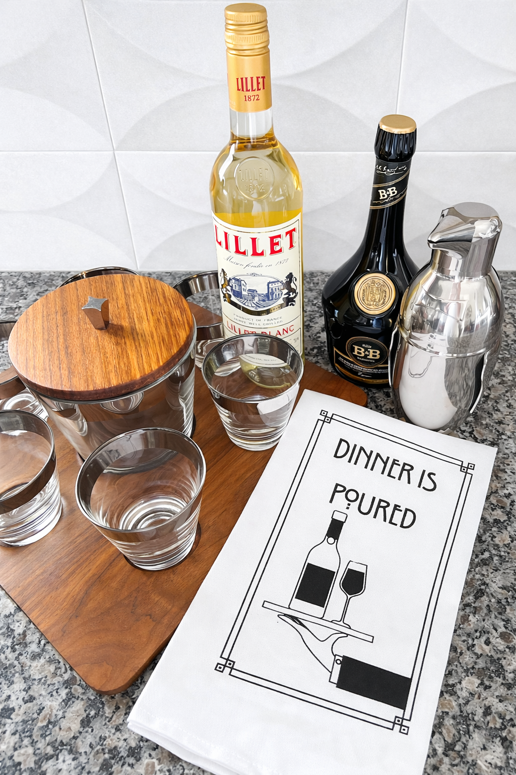 Dinner Is Poured wine kitchen towel styled with barware and glasses