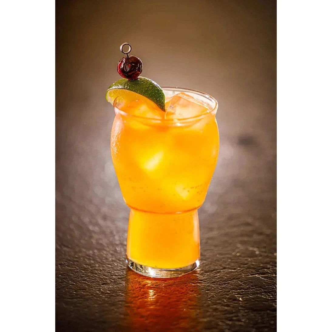 golden cocktail garnished with cherry and lime