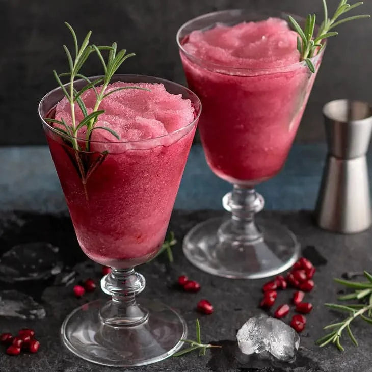 Two glasses of Pomegranate Wine Slushy Mix – Craft Frozen Cocktail Mixer on a dark background