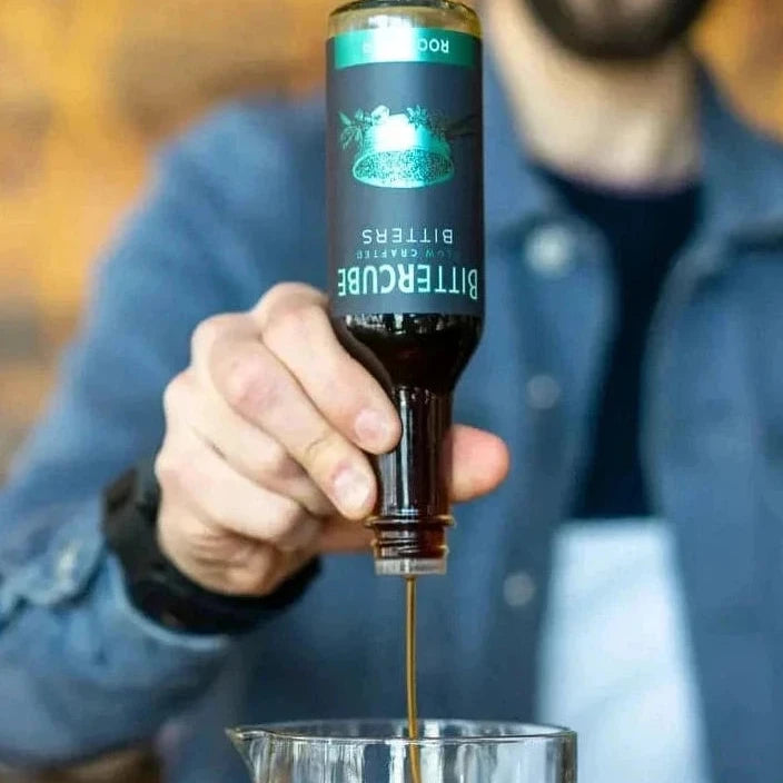 Man pouring bitters into a glass