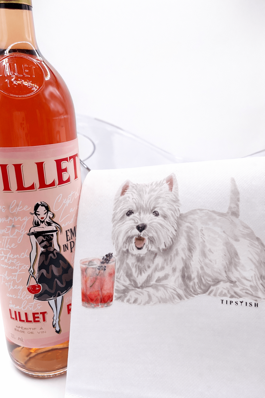 Bottle of Lillet with a tea towel featuring a dog design on a white background