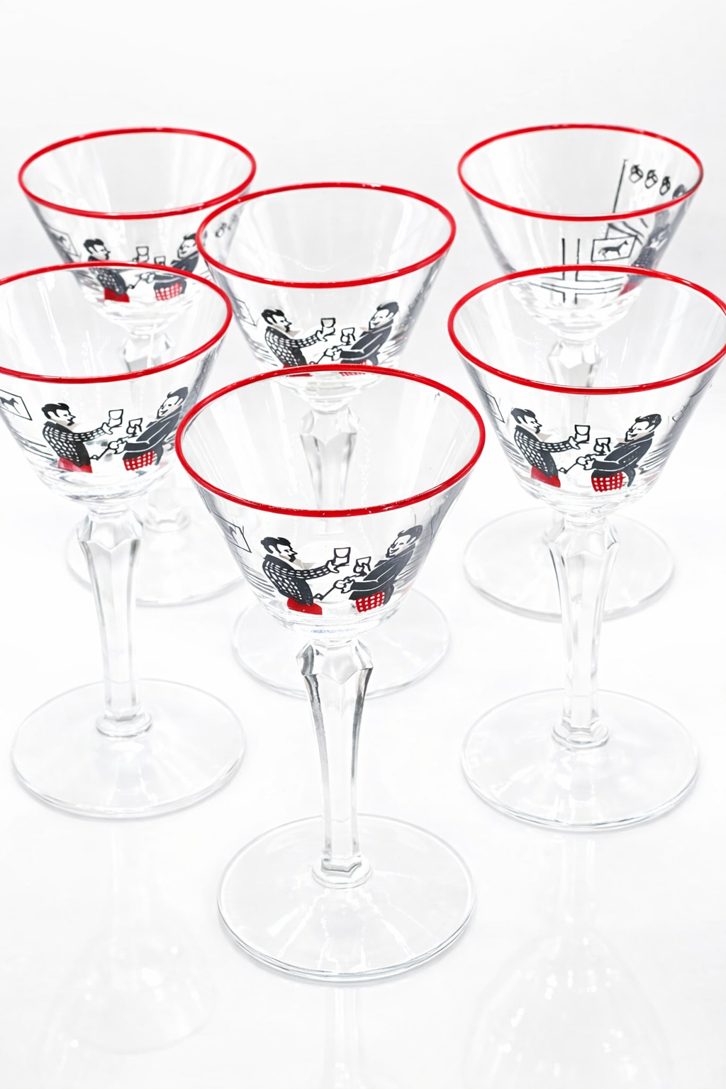 Set of six clear cocktail glasses with red rims and black and white illustrations on a white background