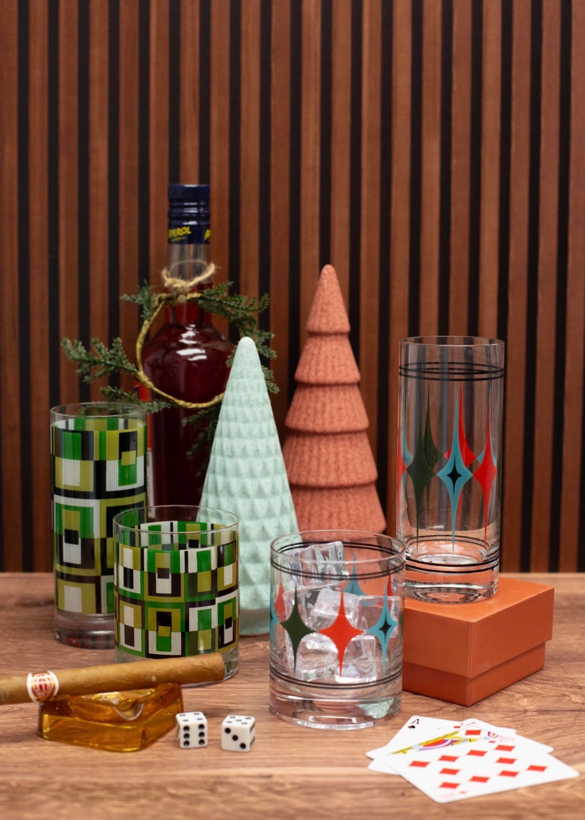 Retro whiskey glass with colorful atomic diamond starbursts and black pinstripes styled with mid century cocktail accessories