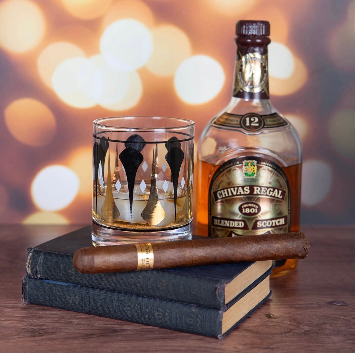 Black and gold mid century whiskey glass styled with Scotch and a cigar for a sophisticated retro bar setting