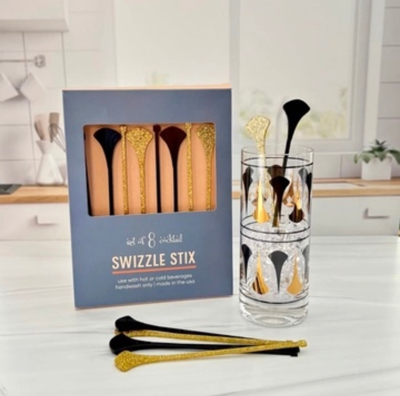 Black and gold dart drink stirrers styled in a coordinating Mid Century Modern cocktail glass.