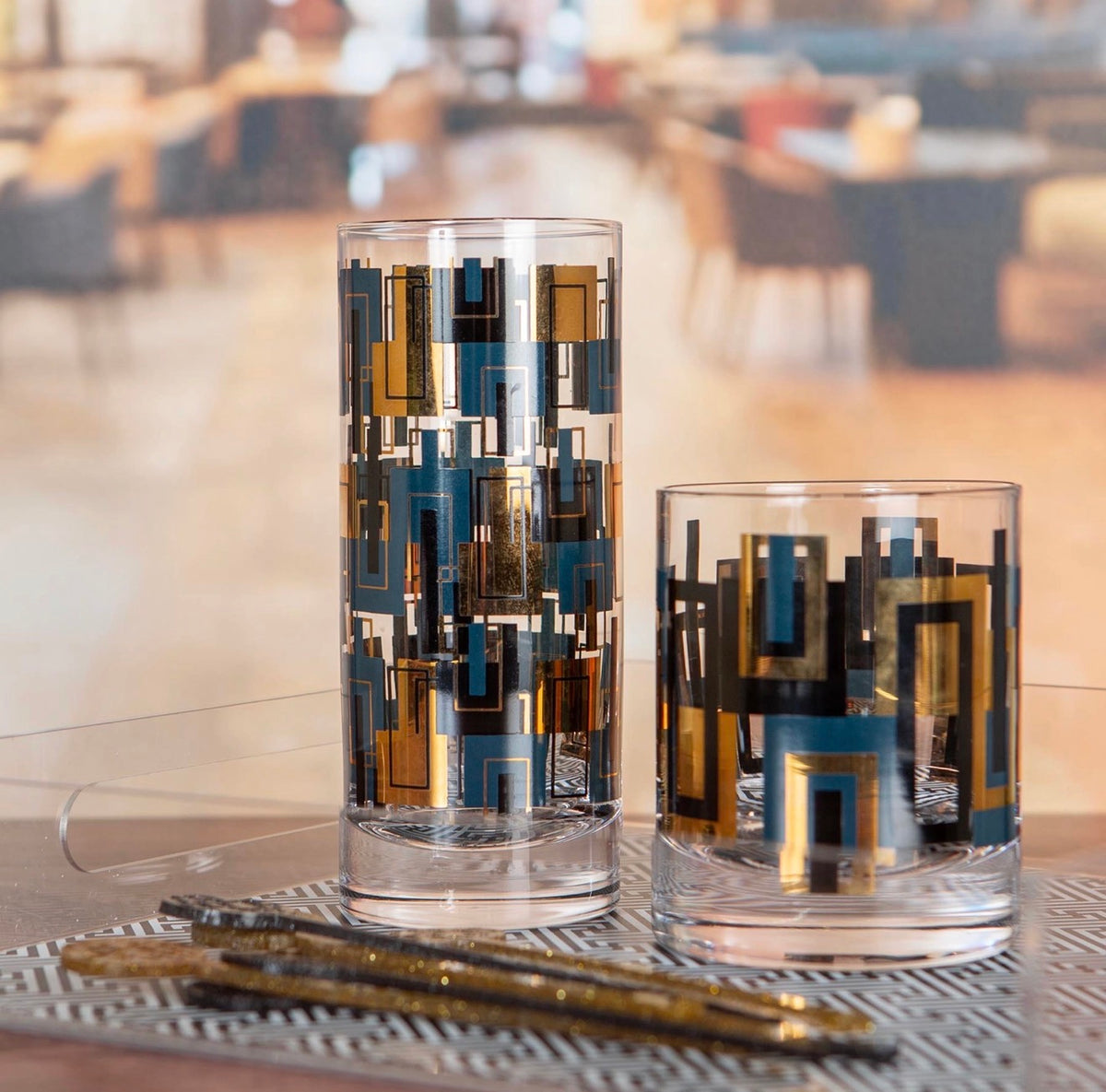 Blue and gold geometric rocks glass displayed with coordinating mid century modern highball glassware