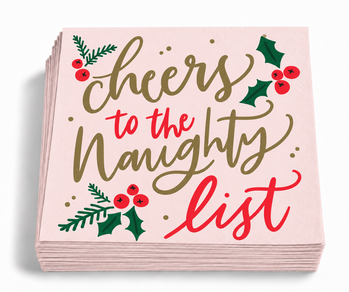 Stack of 20 blush pink Cheers to the Naughty List Christmas cocktail napkins featuring festive red, green, and gold-toned holiday details.