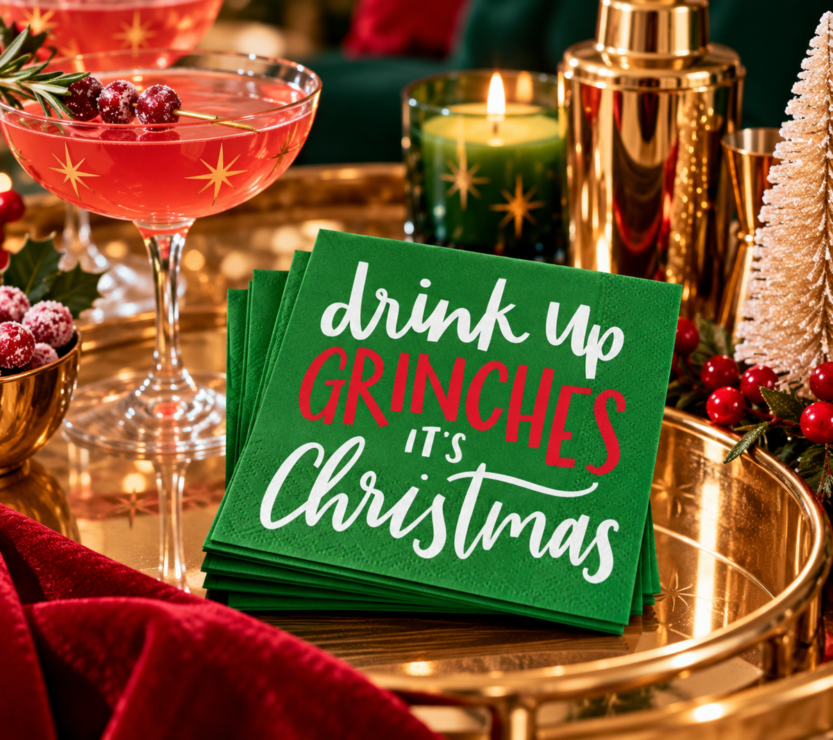 Funny Drink Up Grinches Christmas cocktail napkins styled on a festive gold holiday bar cart with a red cocktail.