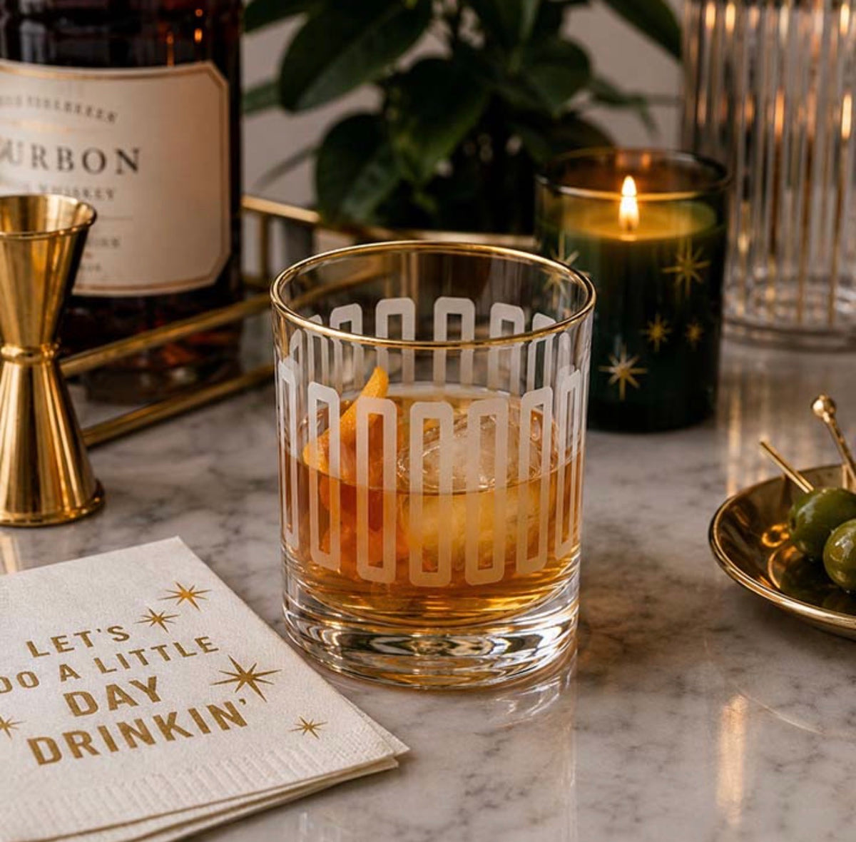 Frosted mid century modern whiskey rocks glass with gold rim styled with an Old Fashioned cocktail