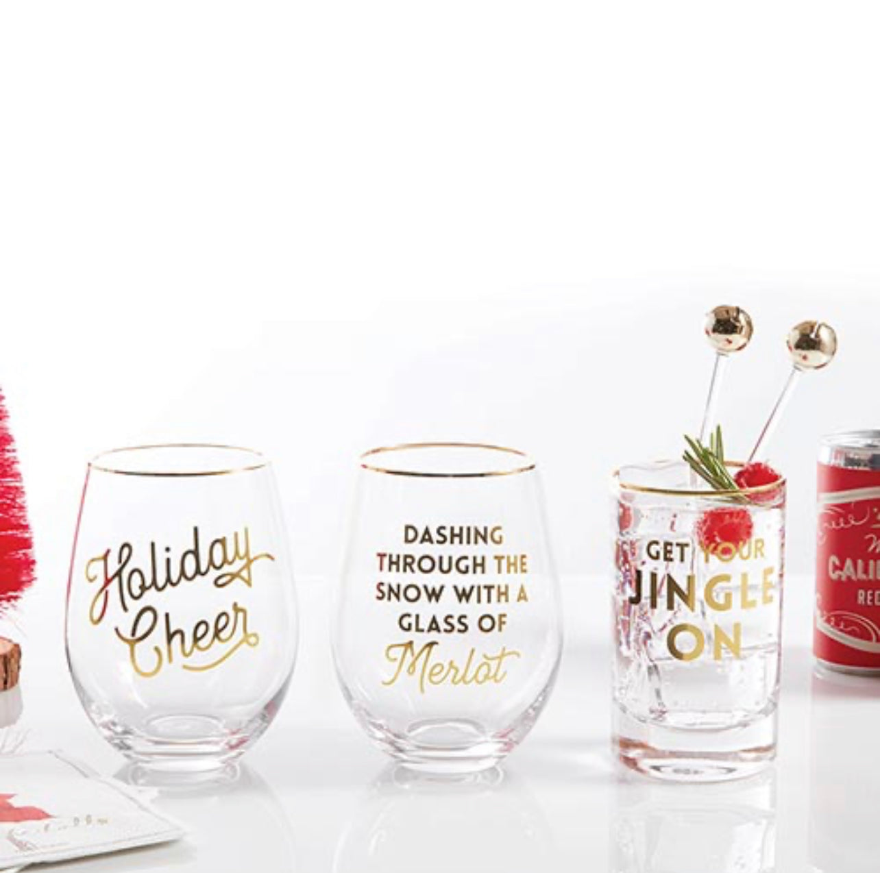 display of three holiday cocktail glasses that are clear with gold rims and gold writing with different Christmas sayings