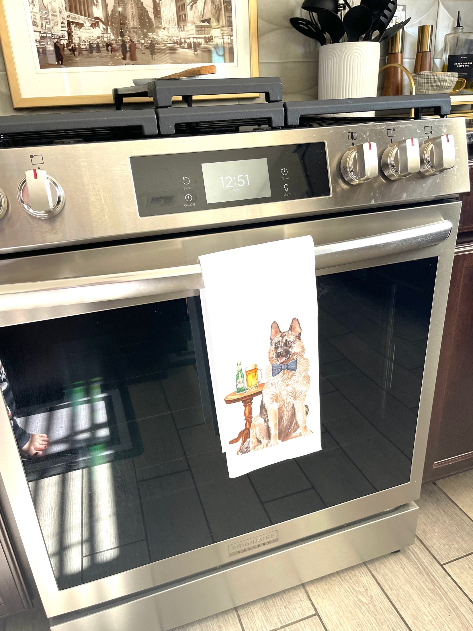 Stainless steel oven with a towel featuring a dog design hanging on the handle.