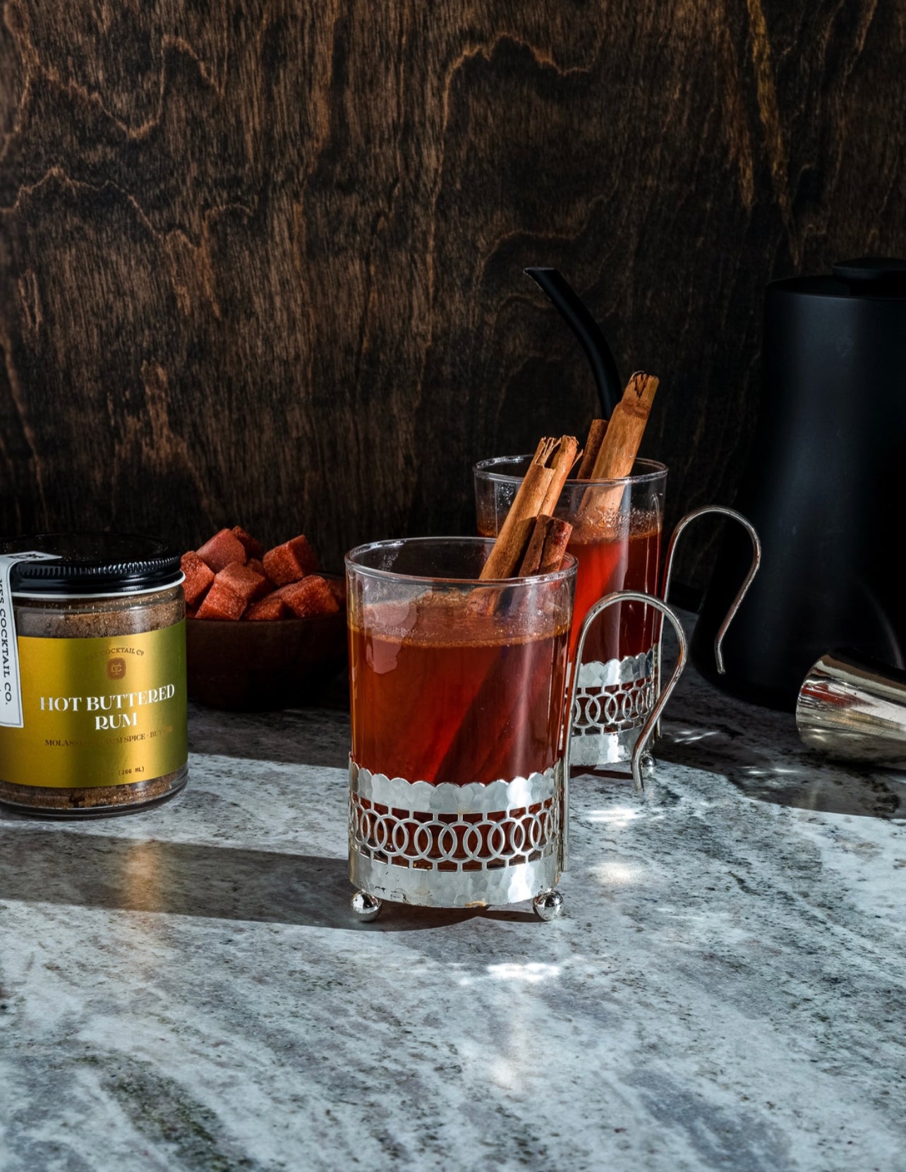 hot buttered rum mix displayed in turkish coffee cups and garnished with cinnamon sticks
