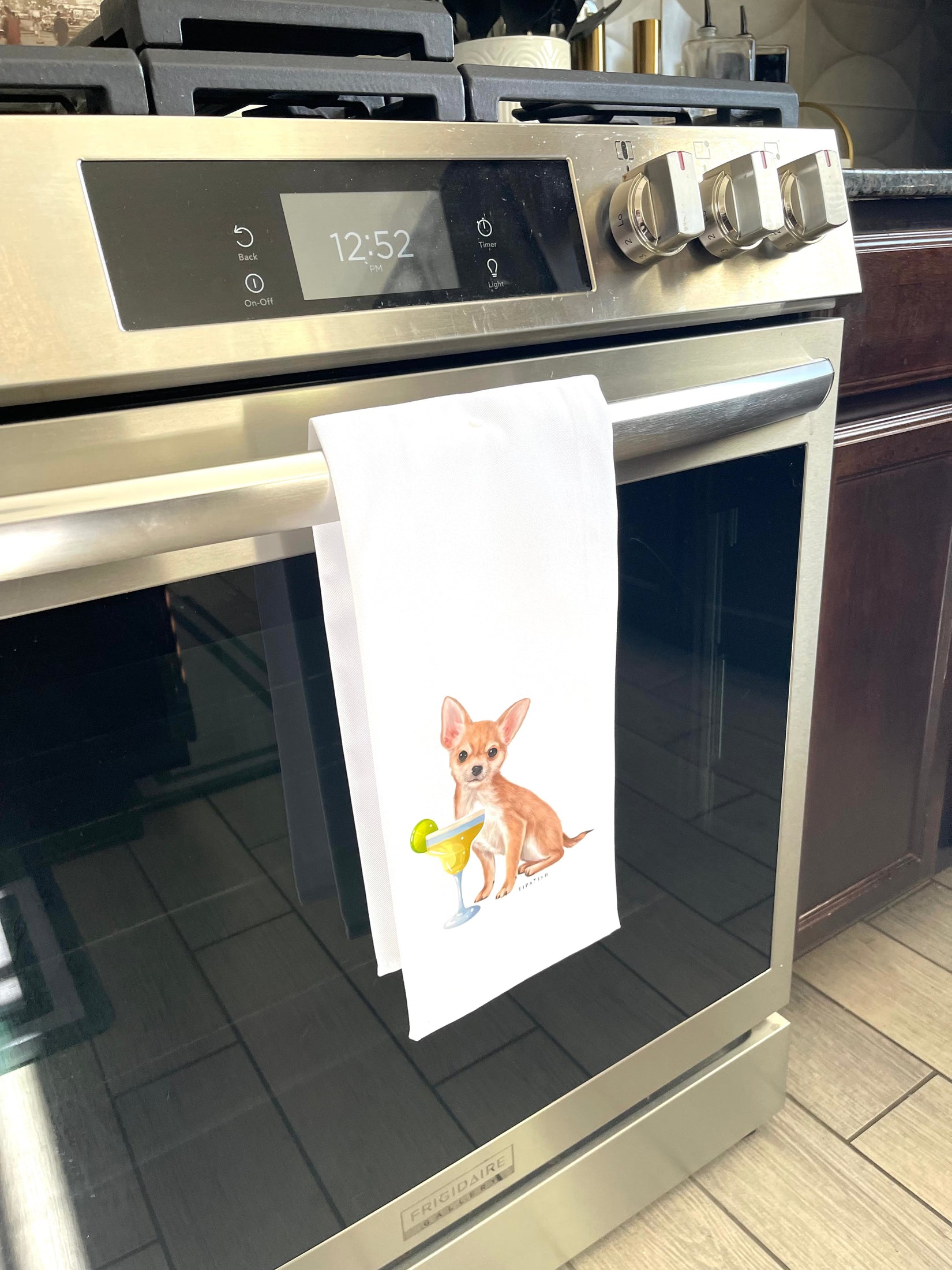 Stainless steel oven with a towel featuring a dog design hanging on the handle.