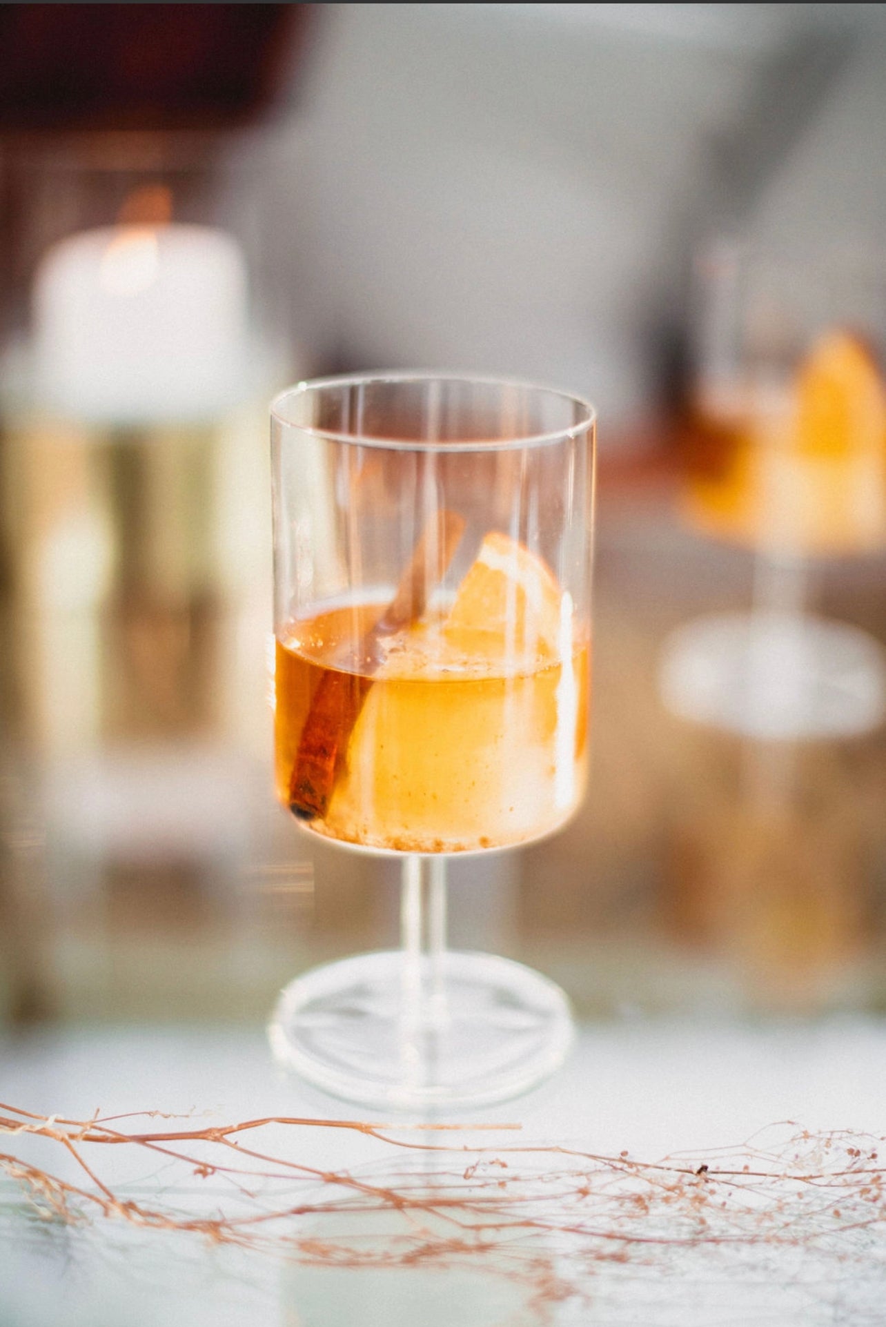 clear stemmed cocktail glass displaying a cocktail made with the Orange Peel and Bitters Mix garnished with a cinnamon stick
