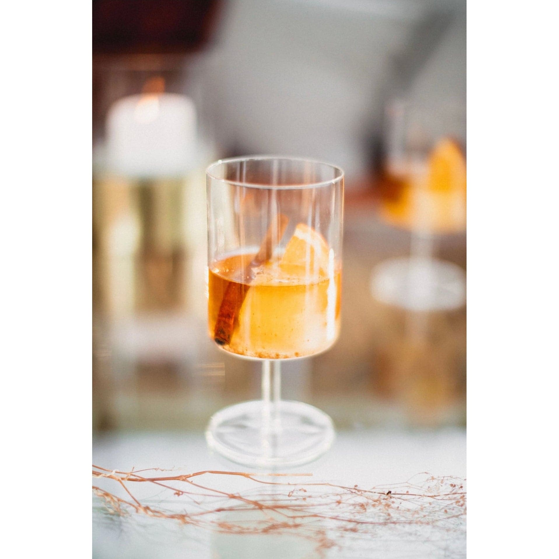 clear stemmed cocktail glass displaying a cocktail made with the Orange Peel and Bitters Mix garnished with a cinnamon stick