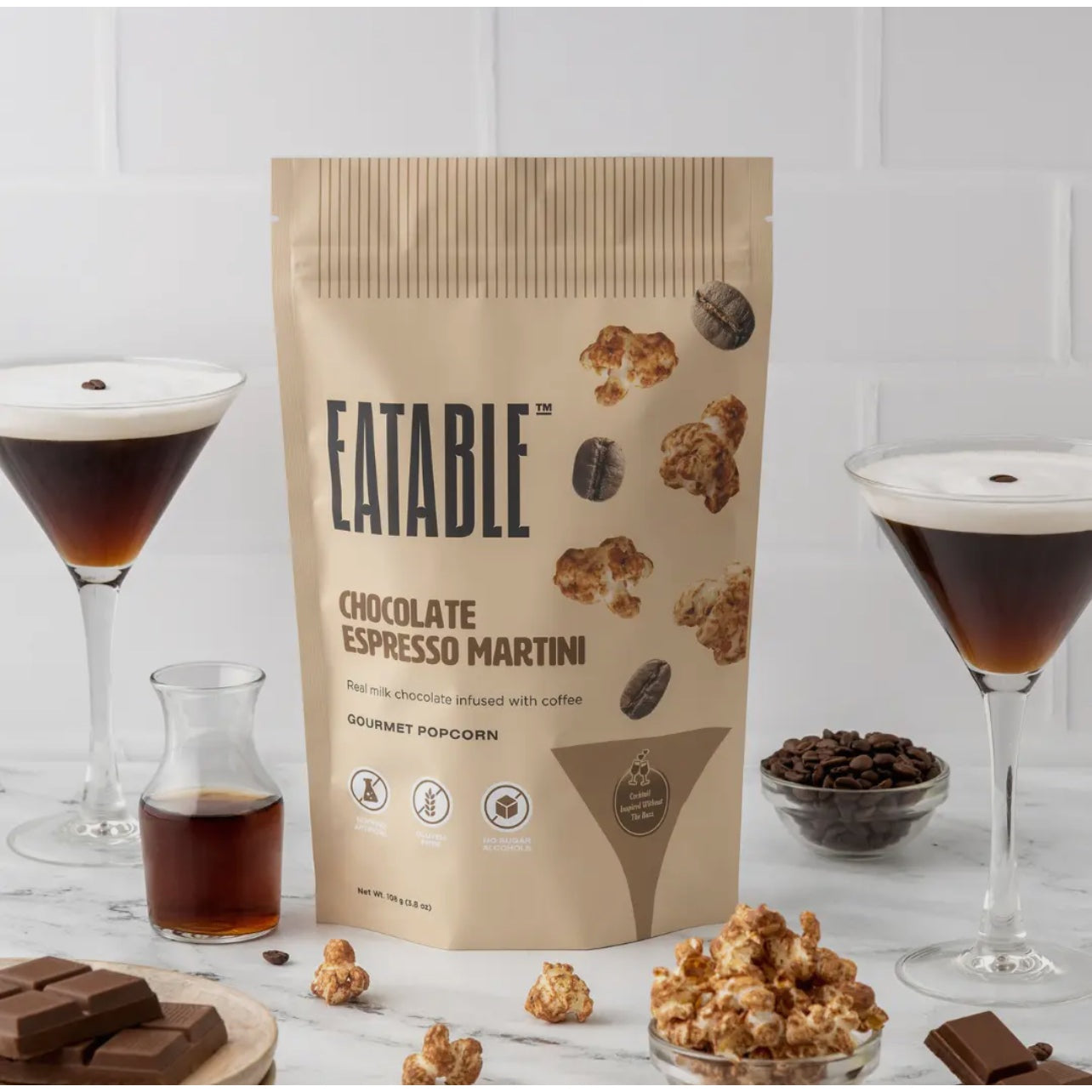 A package of EATABLE Chocolate Espresso Martini gourmet milk chocolate popcorn, with images of popcorn, glasses of espresso martini, and ingredients like chocolate and coffee beans in the background.