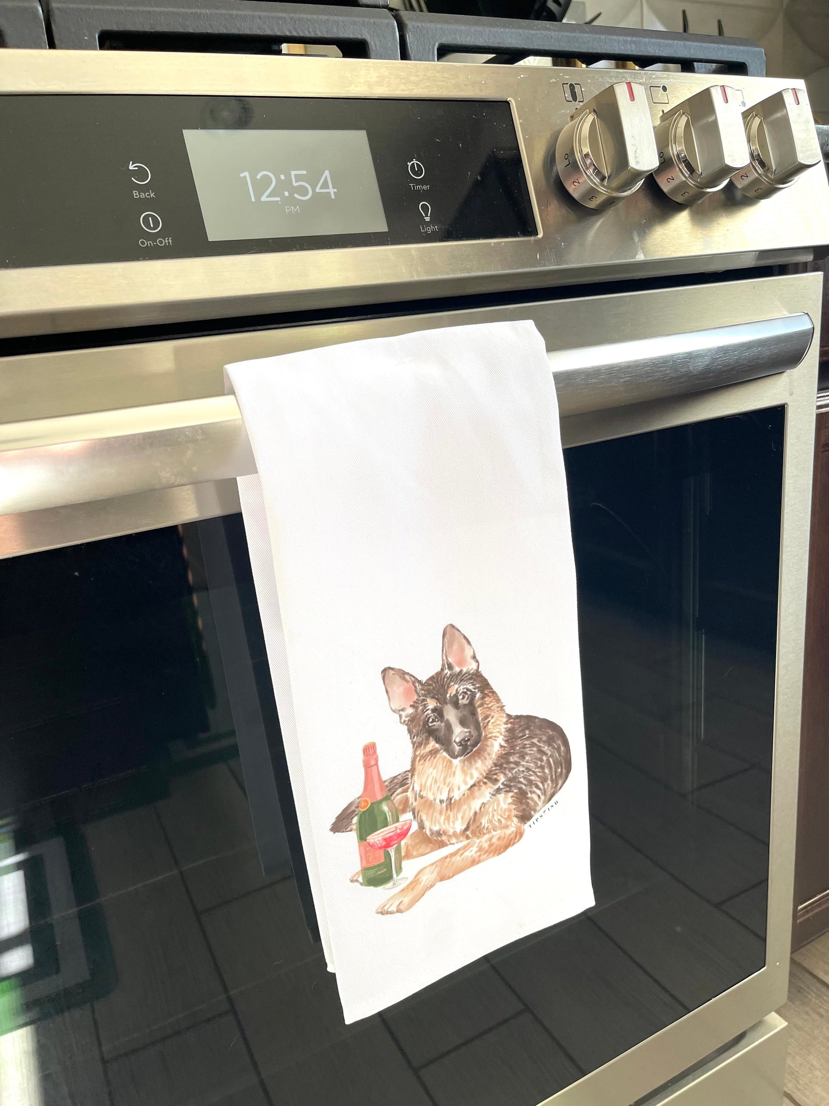 Stainless steel oven with a towel featuring a dog design hanging on the handle.