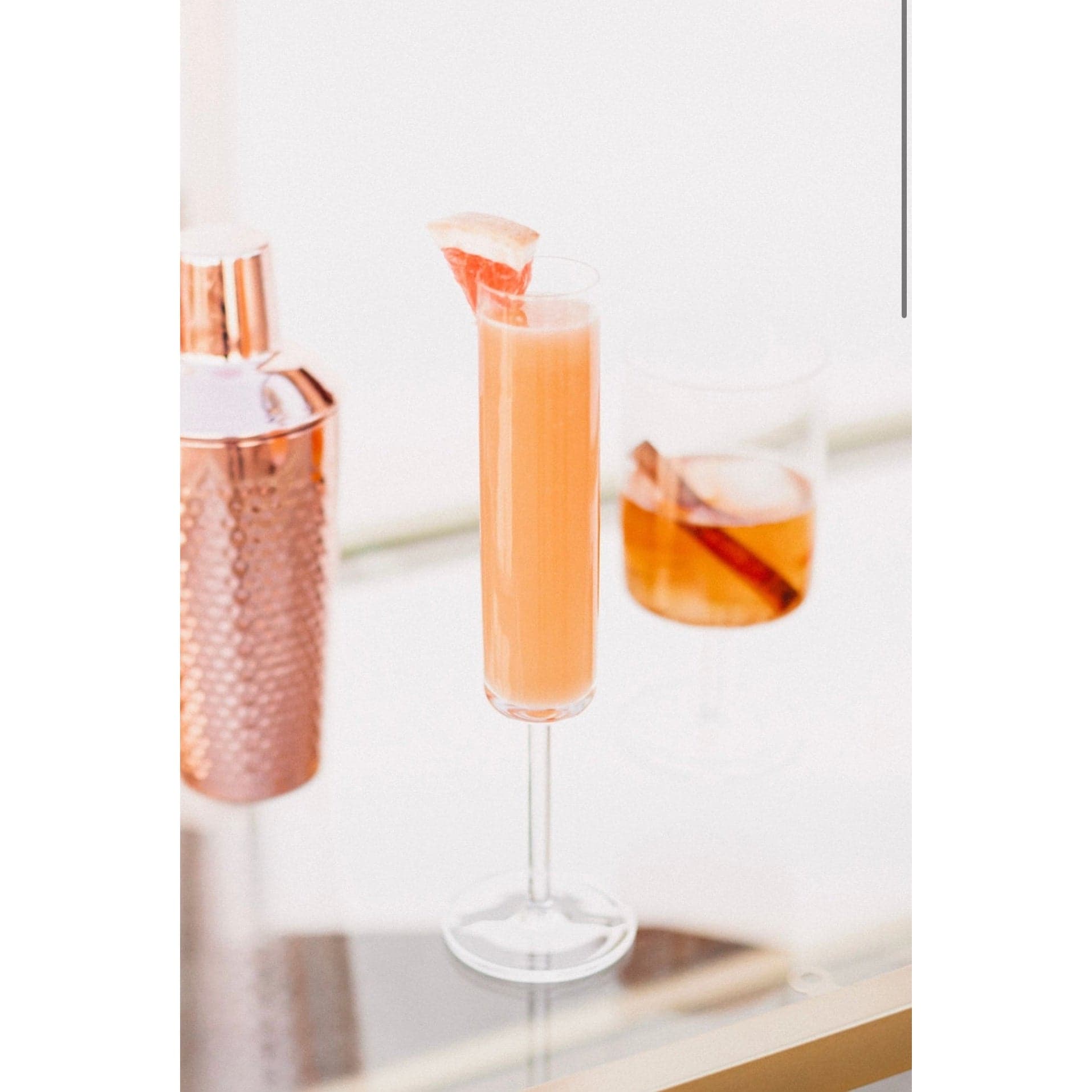 champagne glass and clear stemmed cocktail glass displaying a cocktail made with the Orange Peel and Bitters Mix garnished with a cinnamon stick