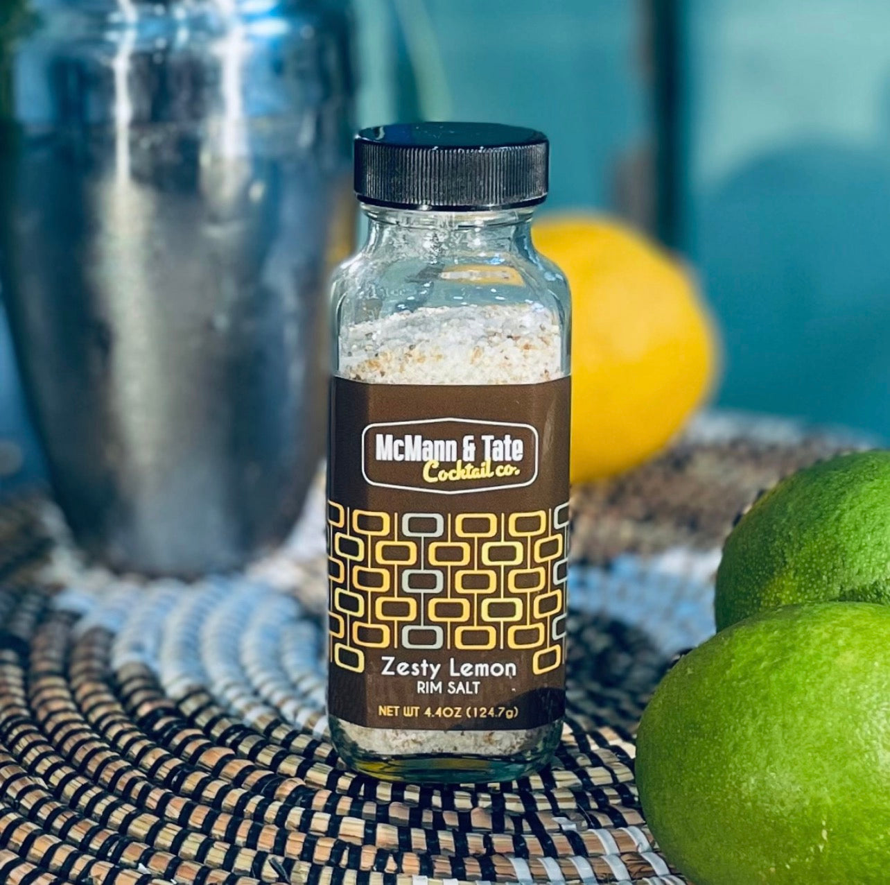 McMann & Tate Zesty Lemon rim salt styled with limes, lemon, and cocktail shaker for home bar use