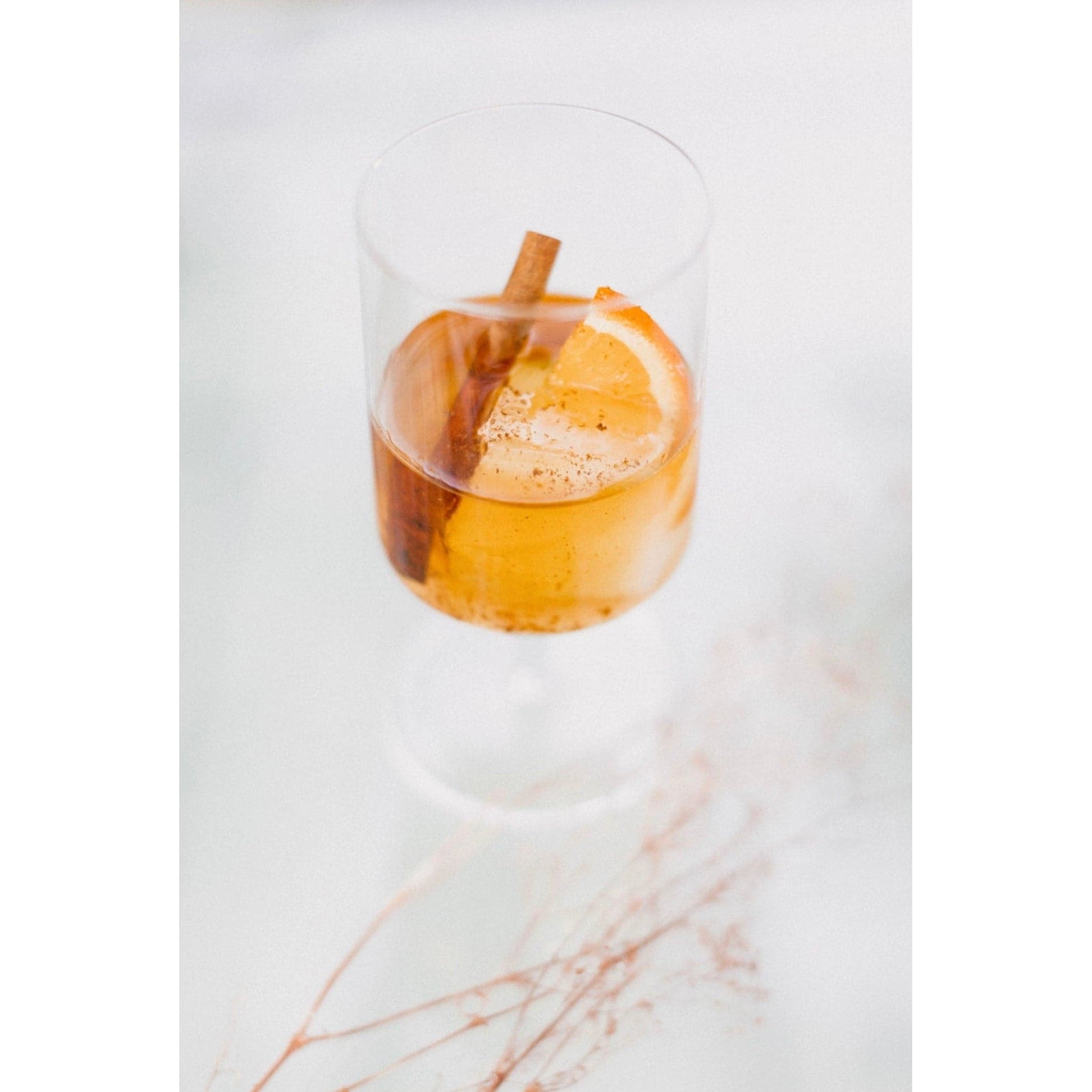 clear stemmed cocktail glass displaying a cocktail made with the Orange Peel and Bitters Mix garnished with a cinnamon stick