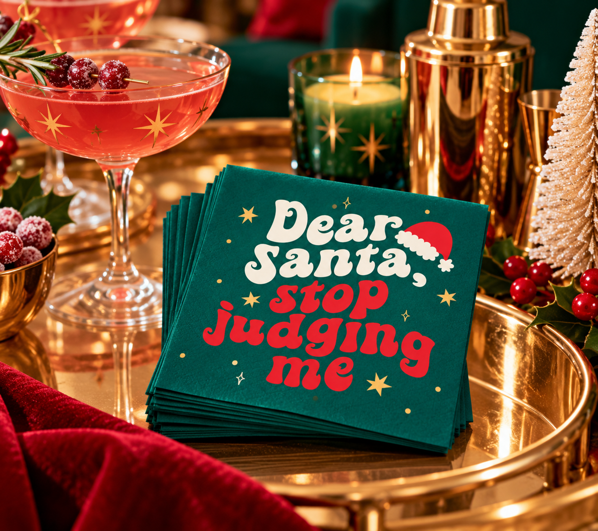 Dear Santa Stop Judging Me Christmas cocktail napkins styled on a festive gold bar cart with a pink holiday cocktail, gold barware and Christmas decor.