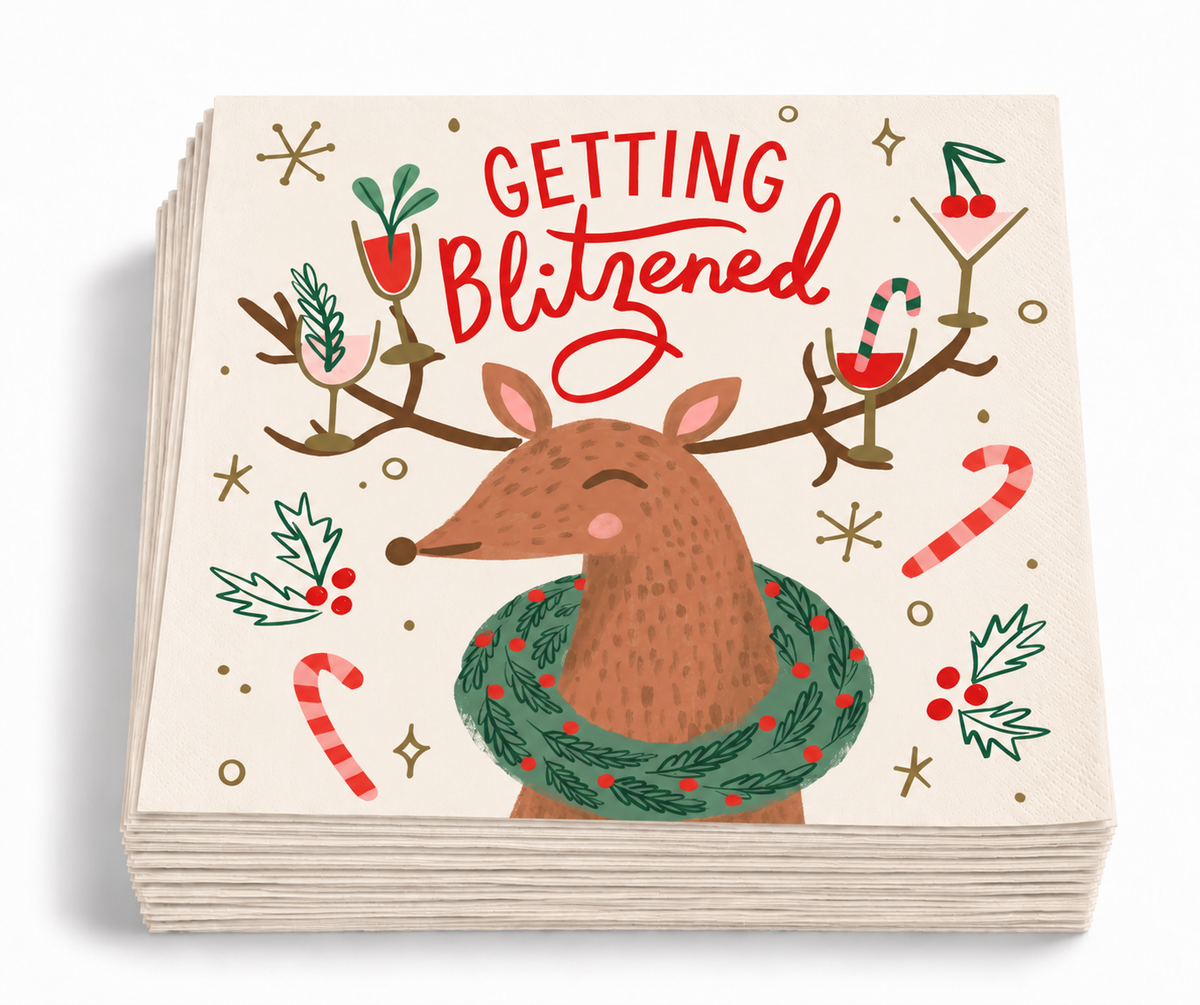 Stack of Getting Blitzened Christmas cocktail napkins featuring a whimsical reindeer with holiday drinks, holly and candy canes.