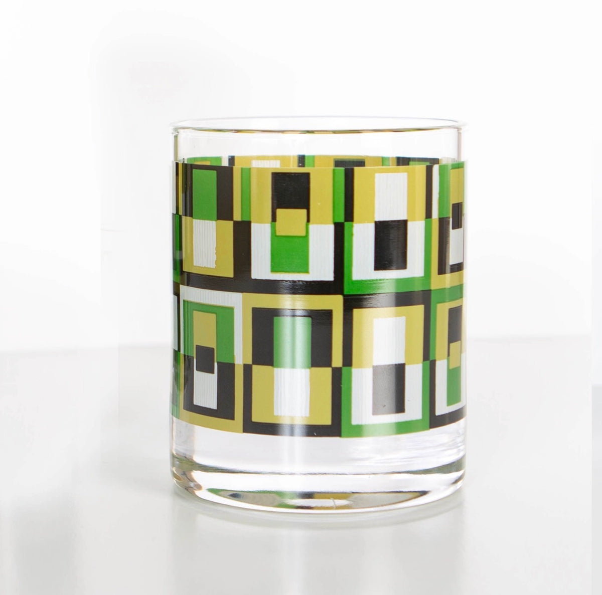 Clear 10 oz whiskey rocks glass featuring an avocado green, olive, black and white geometric square pattern