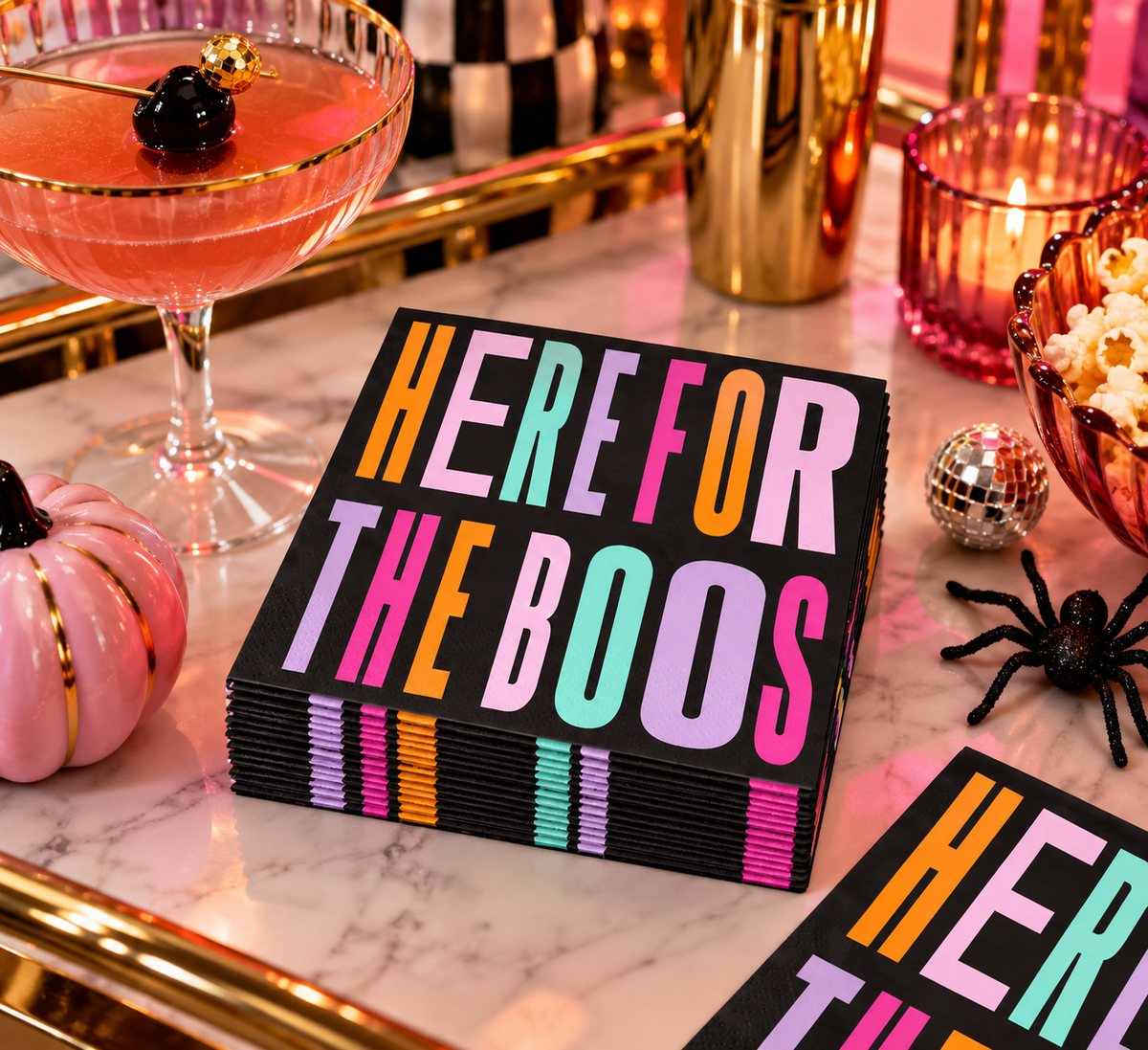 Here for the Boos Halloween cocktail napkins styled with a pink cocktail, gold barware, pink pumpkin and festive Halloween party décor.