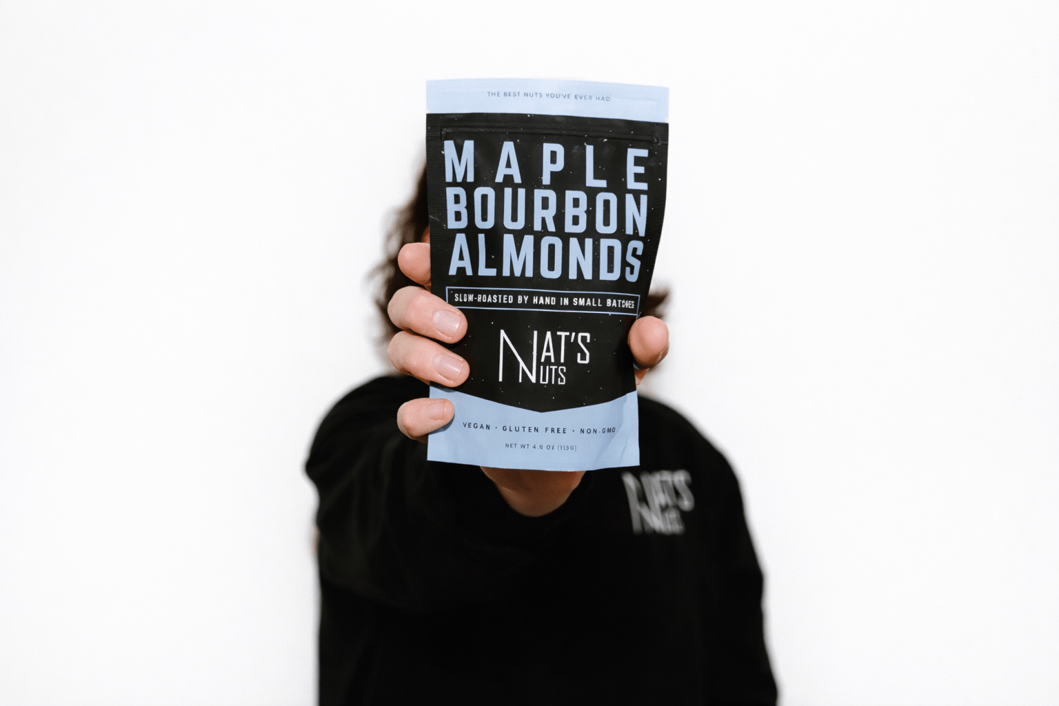 Person holding a package of Maple Bourbon Almonds by Nat's Nuts against a white background