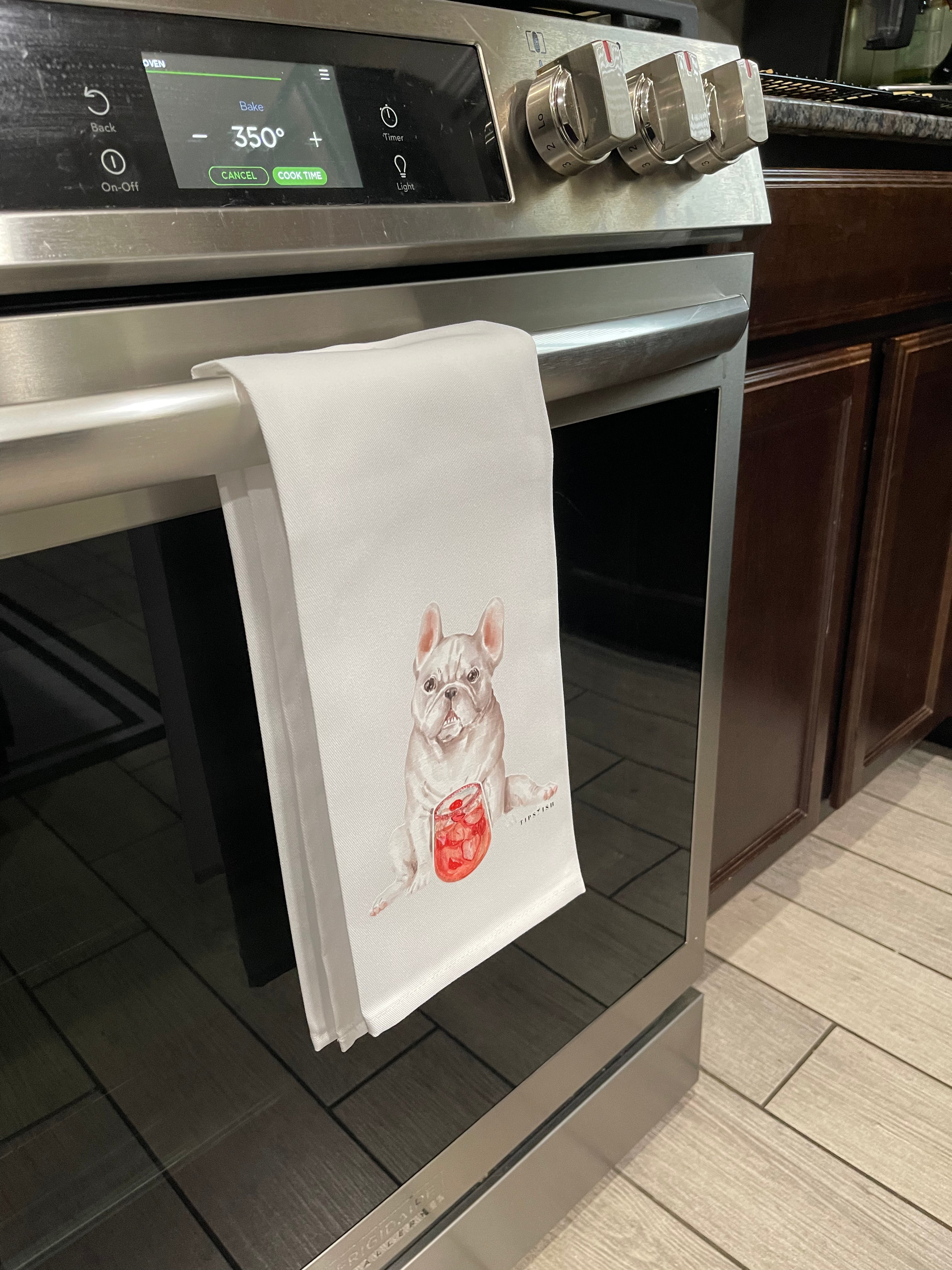 Stainless steel oven with a white tea towel hanging on the handle featuring a French bulldog design 