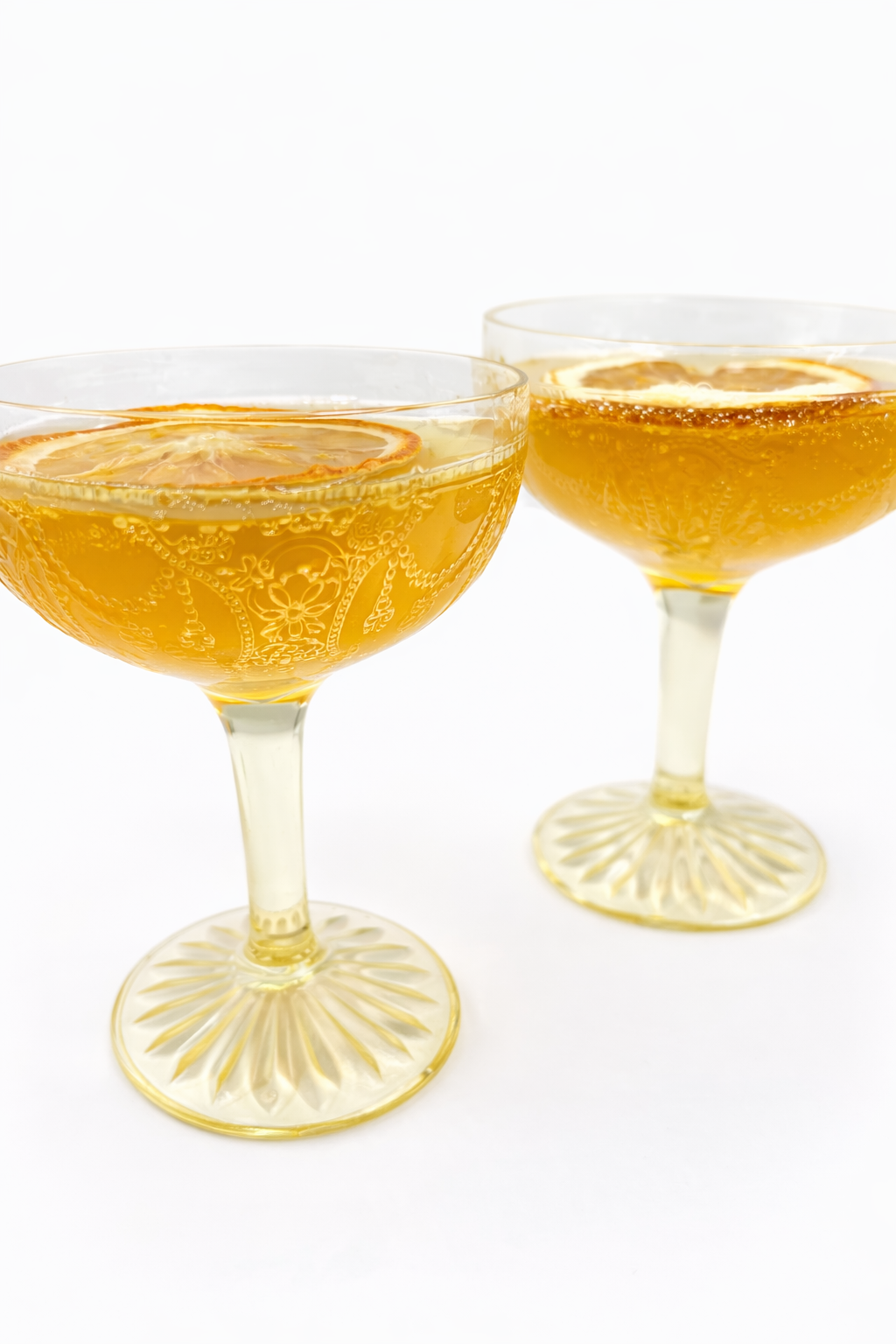 Canary yellow Depression glass coupe glasses filled with sparkling cocktails for mimosa or bellini service