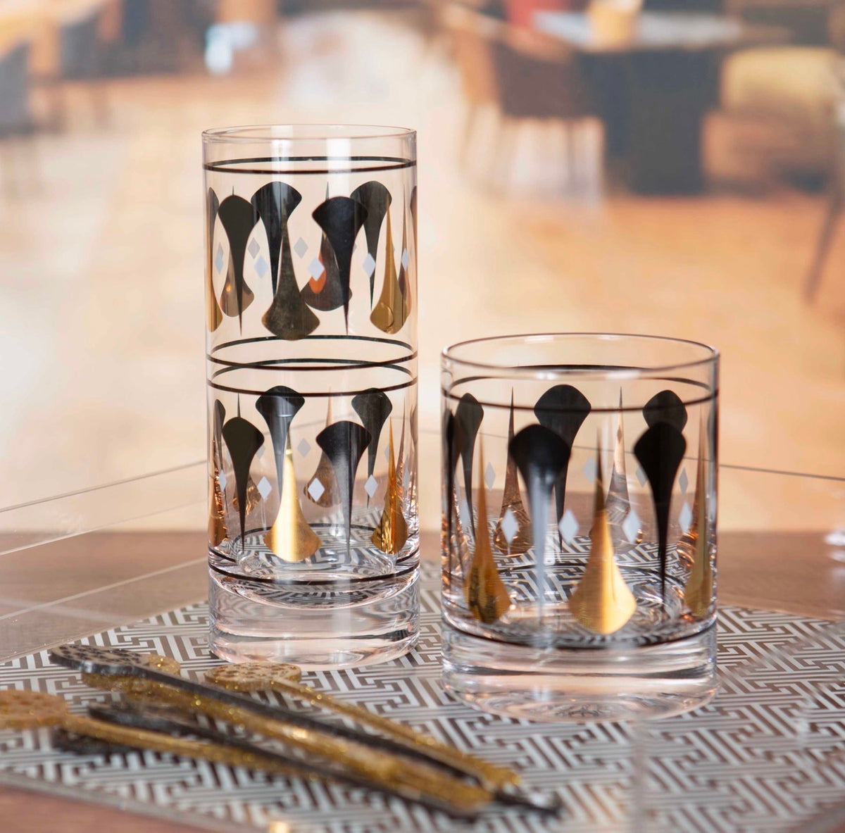 Coordinating black and gold mid century rocks and highball cocktail glasses featuring vintage-inspired dart designs