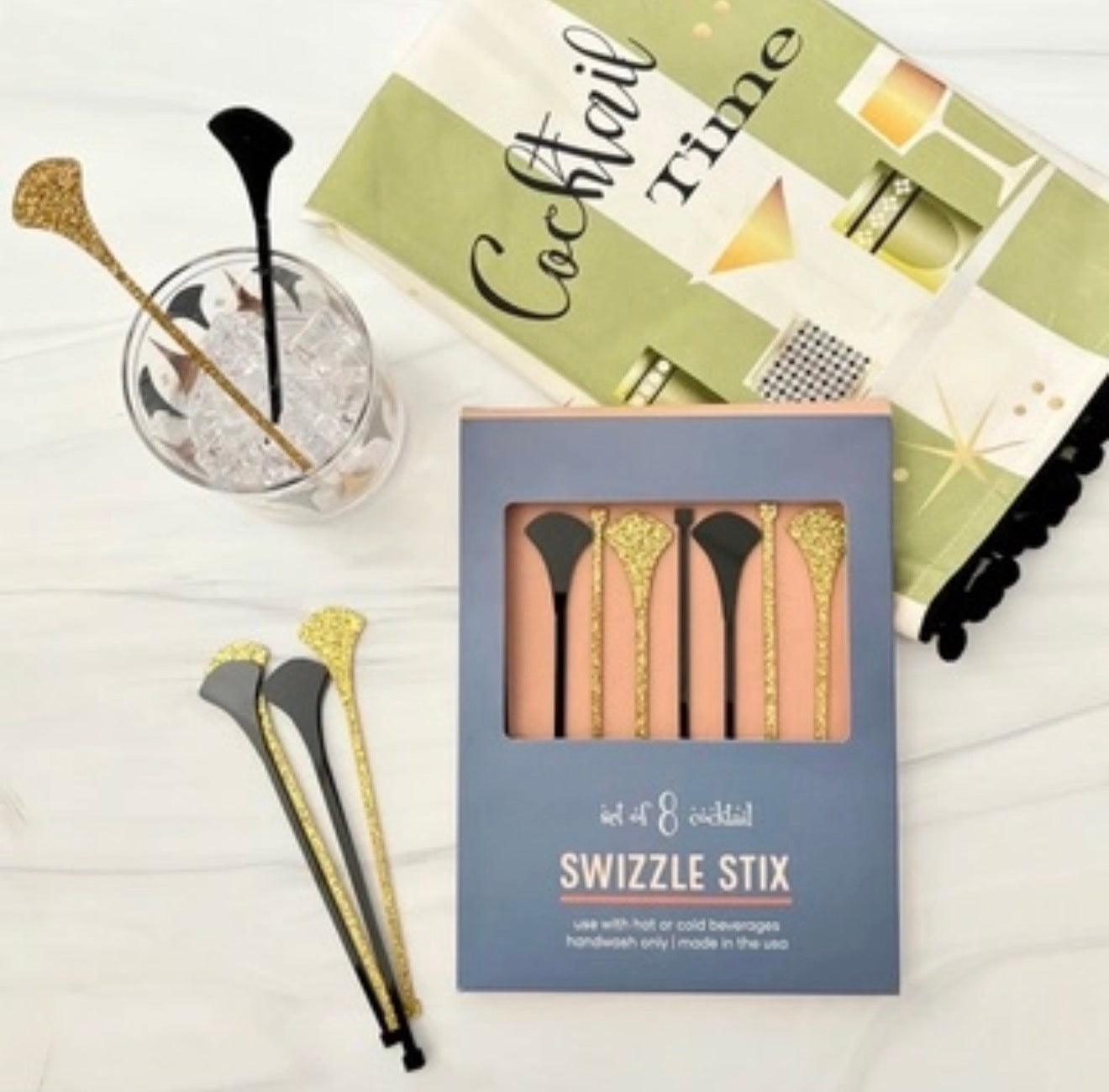 Black and gold acrylic cocktail stirrers displayed with gift packaging and retro cocktail styling.