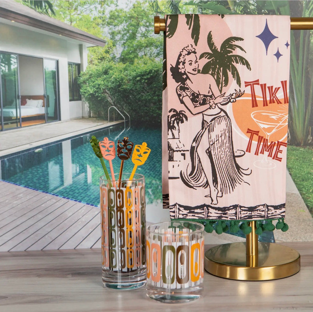 Vintage-inspired tiki rocks glass and highball displayed beside a retro Tiki Time towel in a poolside setting