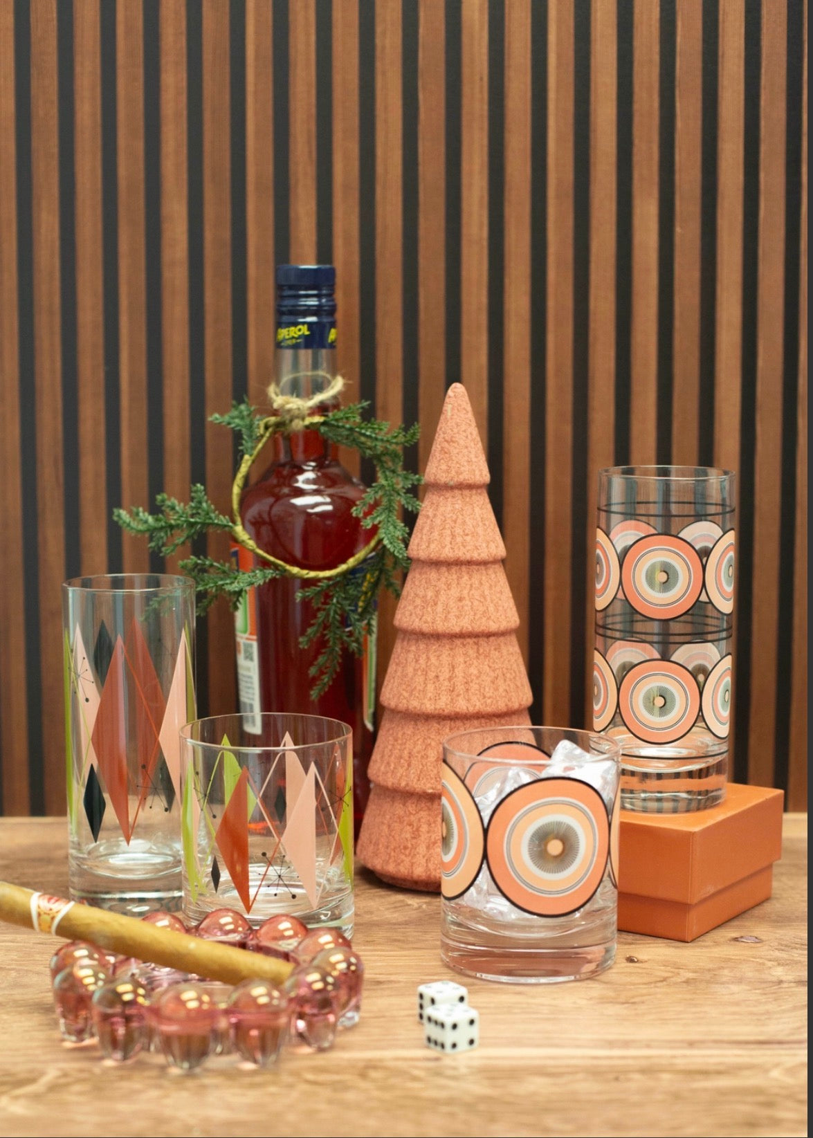 Pink circles whiskey glass displayed with coordinating highball and colorful atomic glassware in a mid century modern bar setting