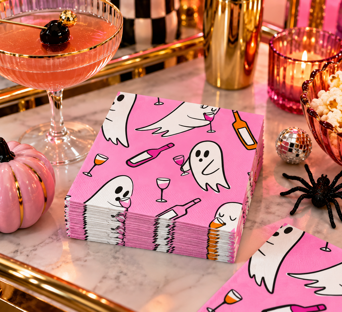 Pink ghost Halloween cocktail napkins styled on a retro bar cart with a pink cocktail, gold barware, pink pumpkin and playful Halloween party décor.