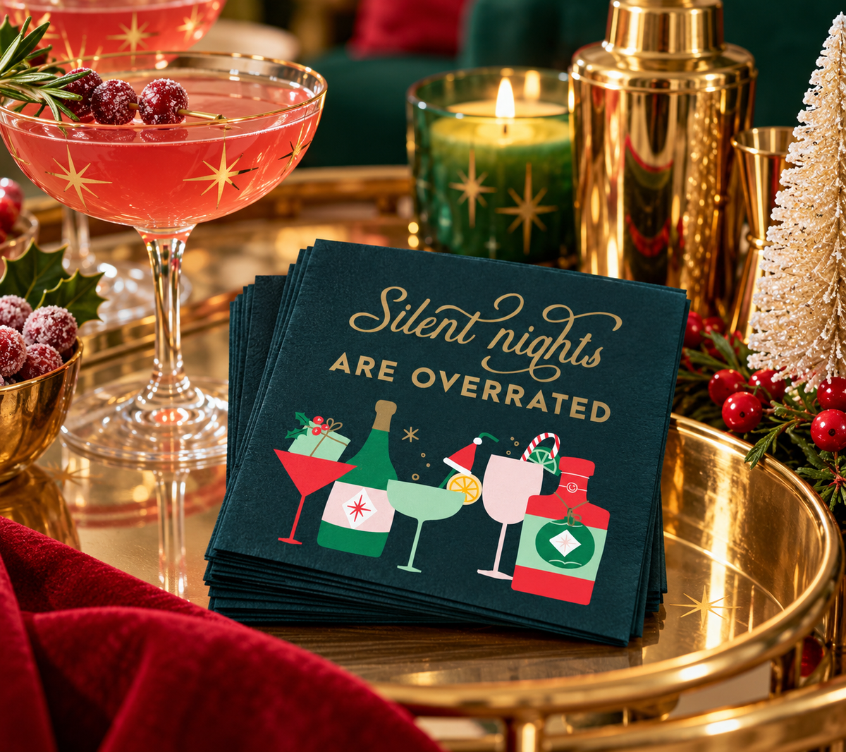 Funny Christmas cocktail napkins styled on a festive gold bar cart with a pink holiday cocktail, vintage-inspired glassware and Christmas decor.