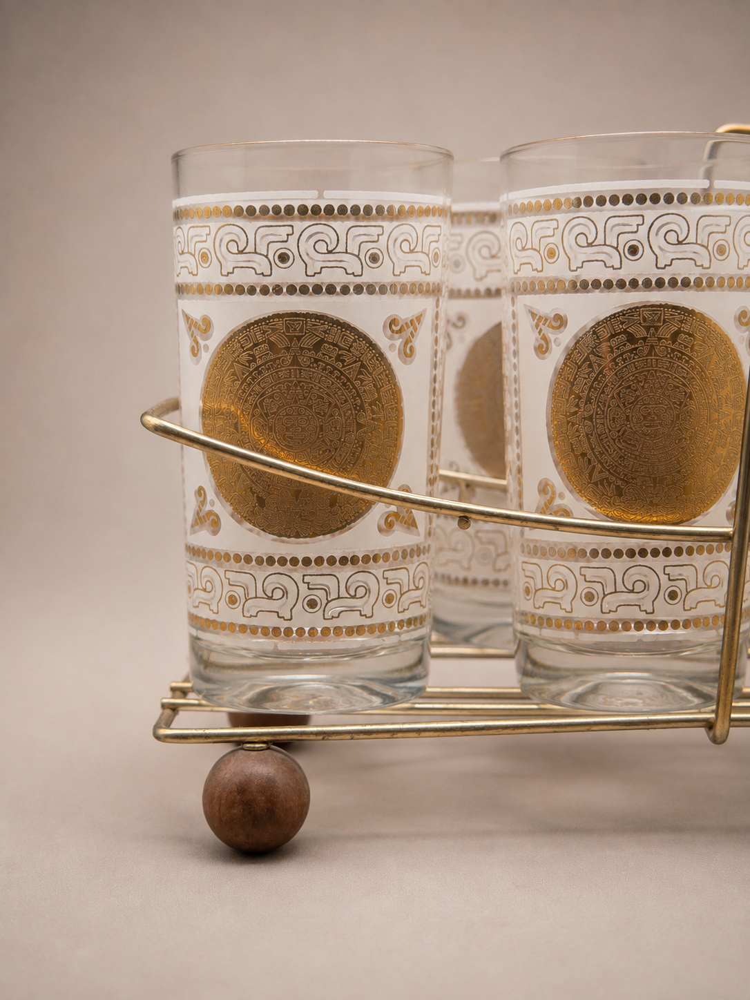 Detailed view of the original brass-tone carrier holding matching Mid Century Modern highball glasses.