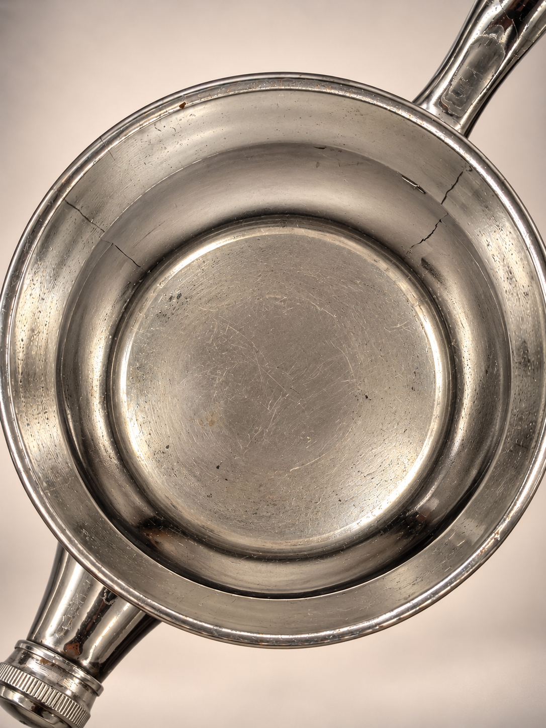 Overhead view of vintage cocktail shaker interior showing scratches, dark spotting, discoloration, and irregular lines along the interior walls.