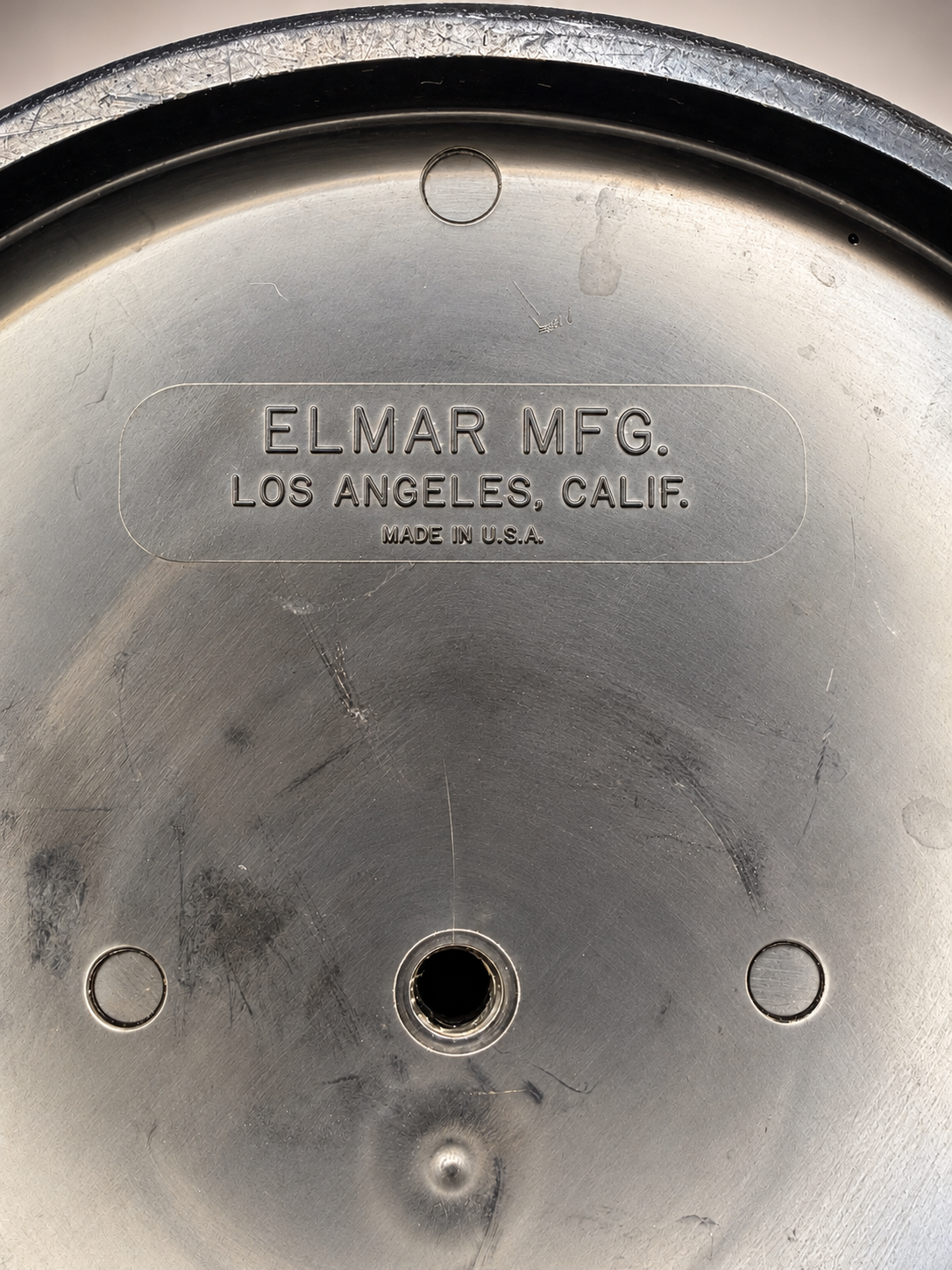 Close-up of original Elmar Mfg. manufacturer’s stamp reading Los Angeles, Calif., Made in U.S.A., with surrounding surface scratches.