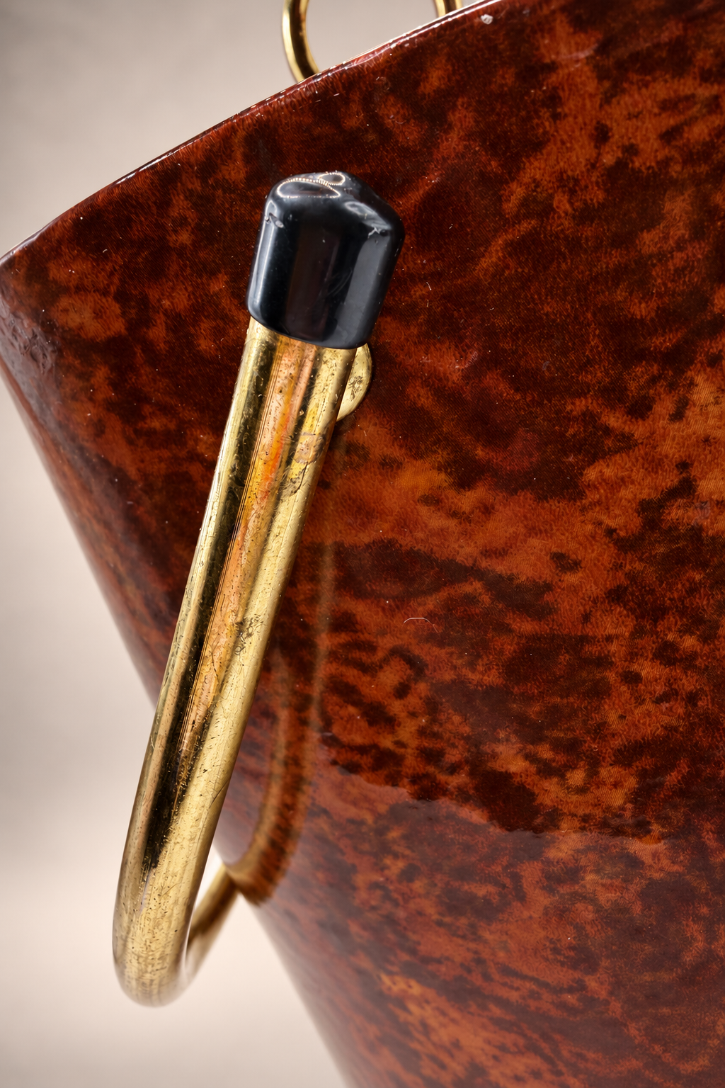 Close-up of gold-tone swing handle with black end cap showing scratches and age-related finish wear.