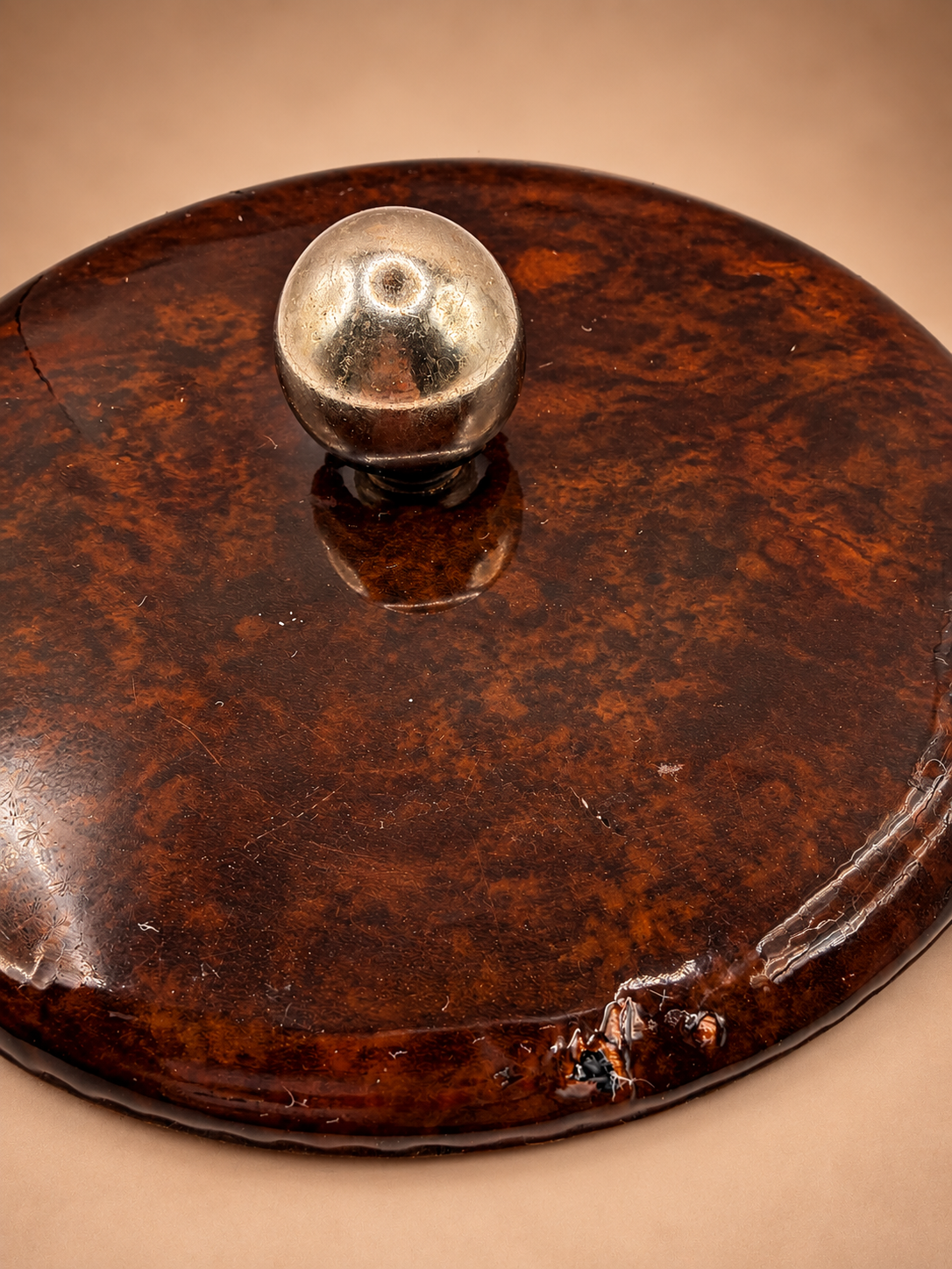 Close-up of vintage brown ice bucket lid showing gold-tone finial, surface wear and localized blemish along outer edge.