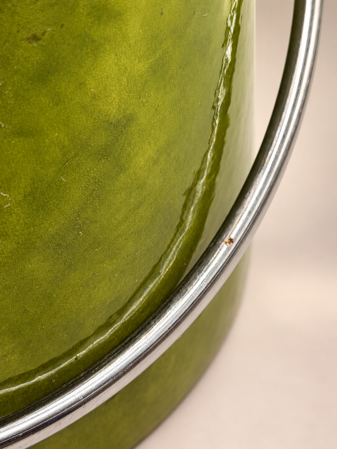 Close-up of silver-tone swing handle against textured green exterior showing a small rust-colored spot and minor surface wear.